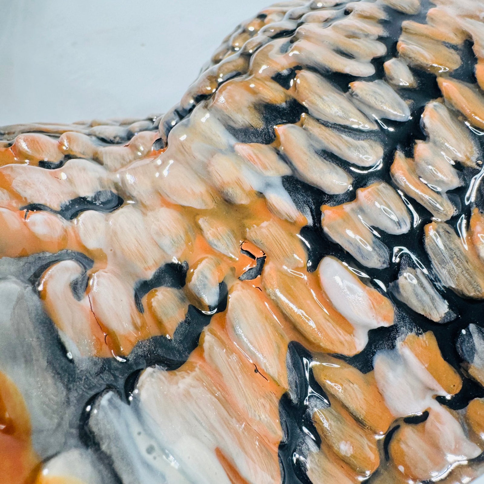 Close up of glossy feather glaze on a ceramic turkey, showing a small buckled glaze spot