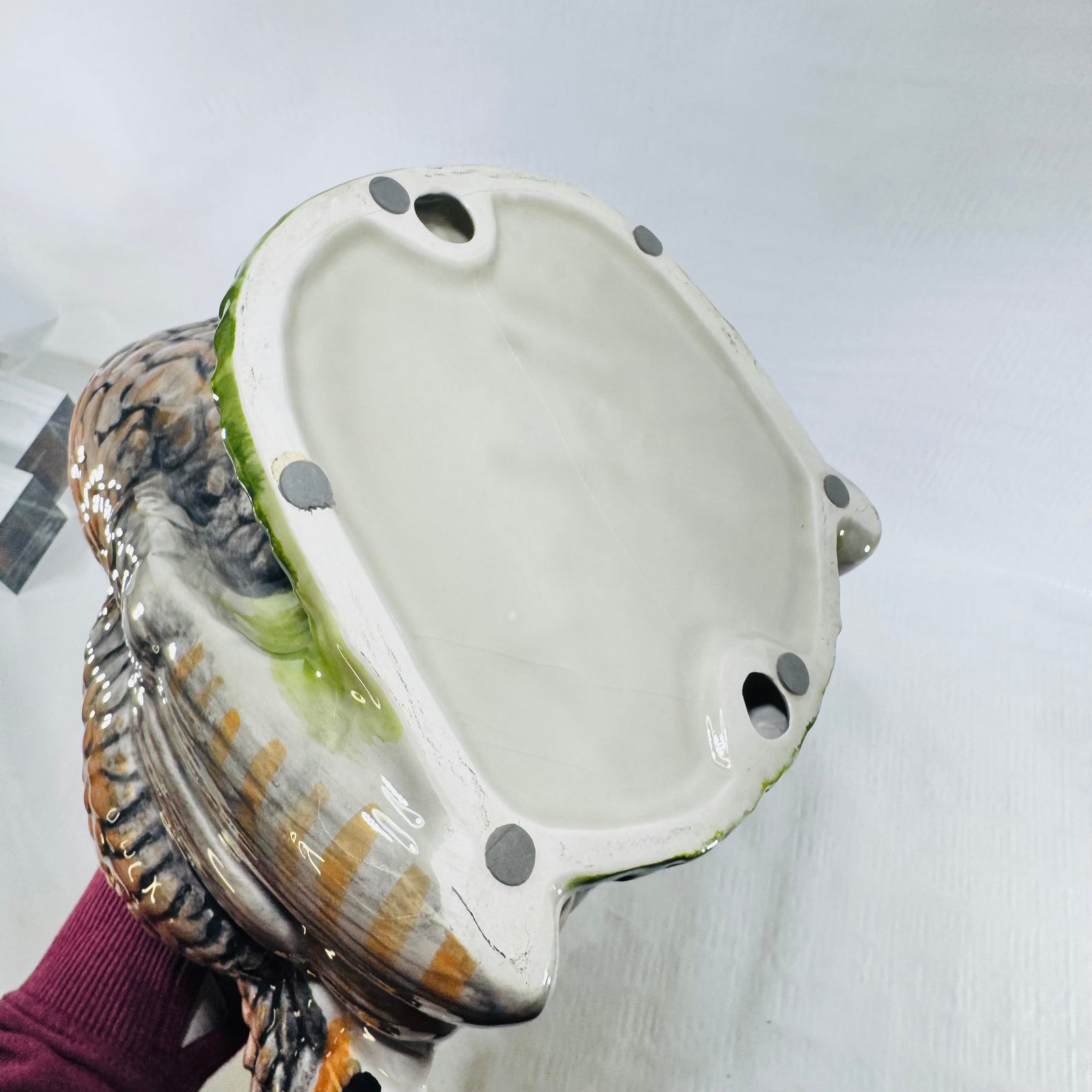 Glazed underside of a hollow ceramic turkey with kiln stilt marks and two holes