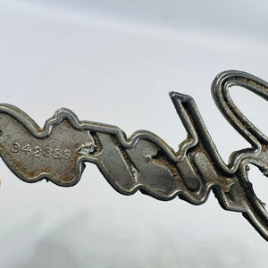 Close view of stamped 342389 part number on Chevrolet grille emblem