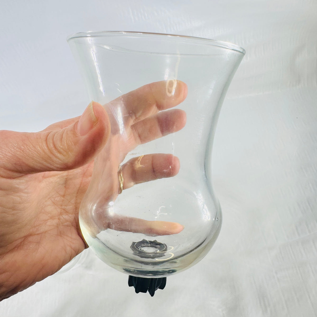 Large clear glass tulip votive cup with a black rubber gripper on the peg.