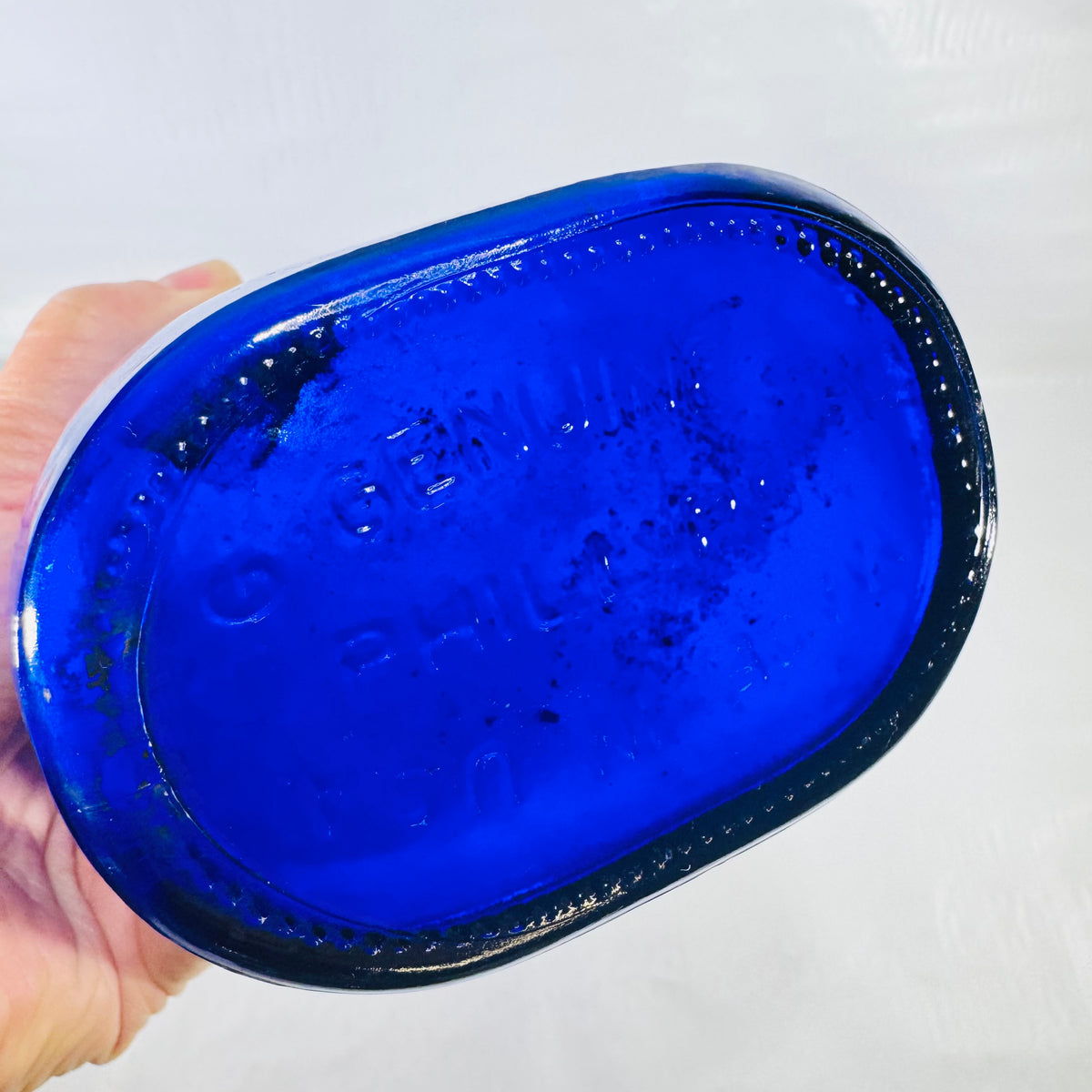 Base of the cobalt bottle with raised GENUINE PHILLIPS' lettering and a stippled edge.