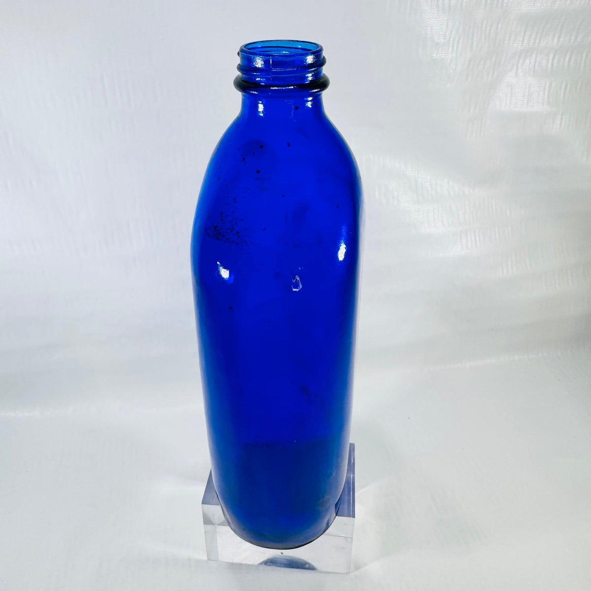 Other side of the cobalt bottle with dark specks visible inside the shoulder.
