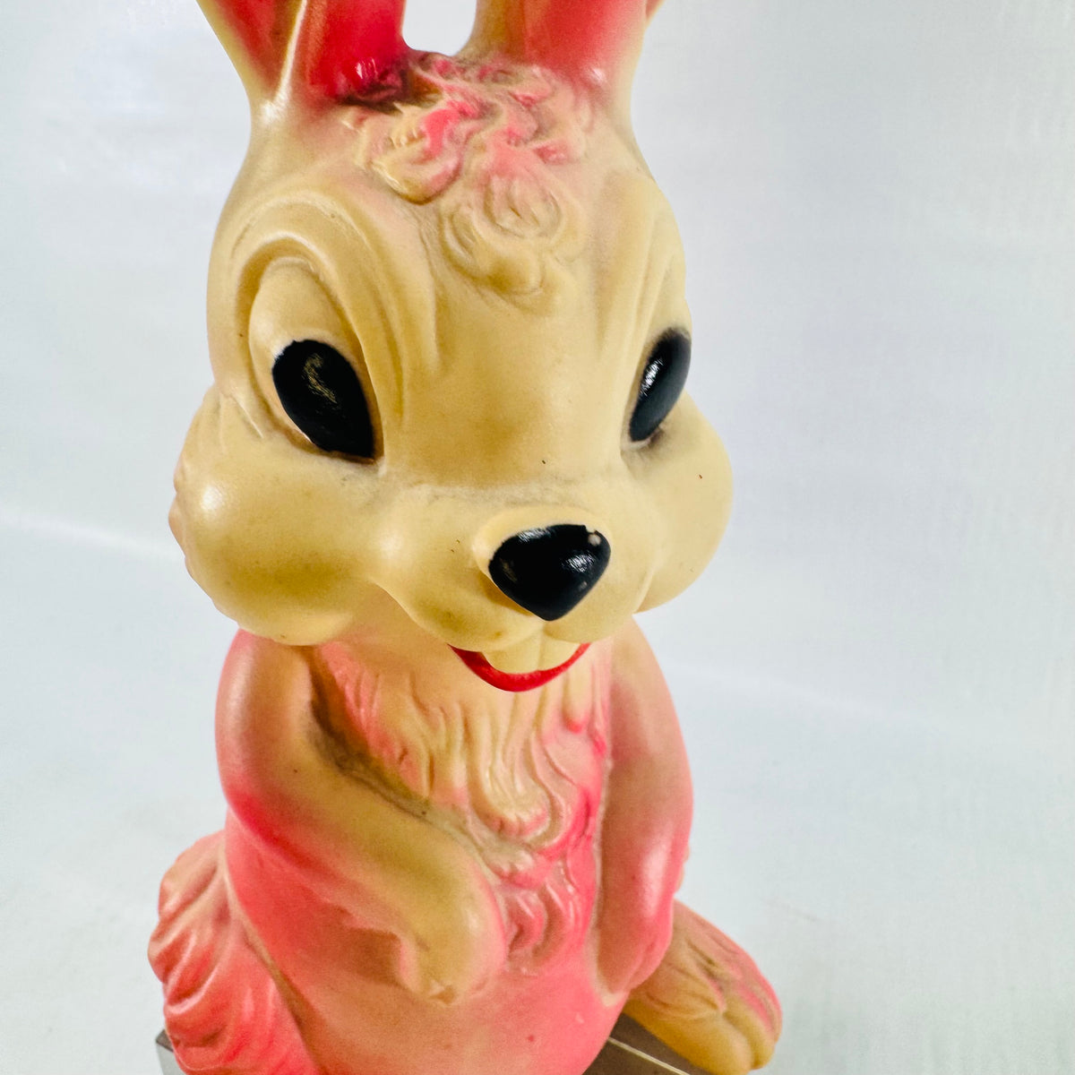Close up of the rabbit face and chest showing glossy black eyes, a red smile, and molded fur.