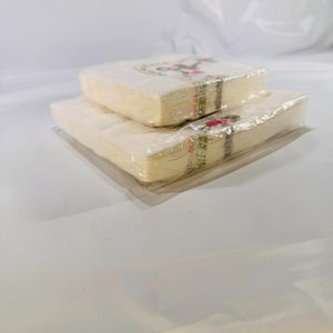 Side view of both sealed napkin packs stacked to display thickness and unopened edges