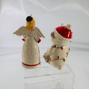 Overhead view of Lenox® holiday ornaments: a porcelain angel figurine with outstretched wings holding festive bells and a porcelain teddy bear wrapped in colored Christmas lights, each approximately 4 inches tall