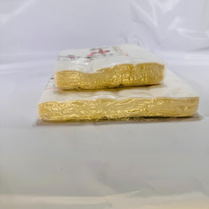 Side view of both sealed napkin packs stacked to display thickness and unopened edges