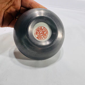 Underside of cloisonné bowl with a white circular porcelain insert stamped “Chinese Porcelain Inlaid in Hong Kong,” set into a dark metal base.