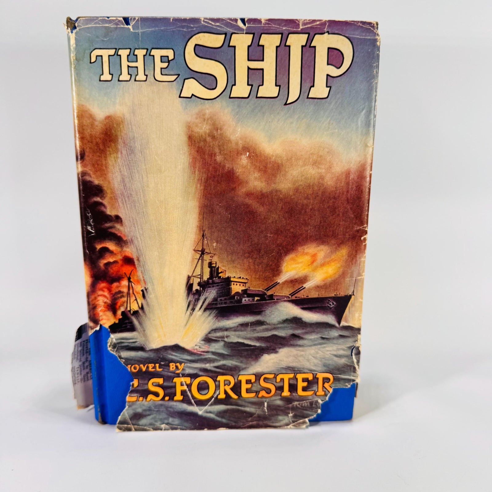 Front jacket of The Ship by C. S. Forester, Sun Dial Press 1944, showing battle-scene art with chips and tears; blue cloth boards beneath.