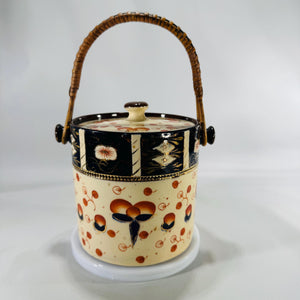 Imari-style ceramic biscuit barrel with black, orange, and gold hand-painted motifs and rattan-wrapped handle, matching lid.