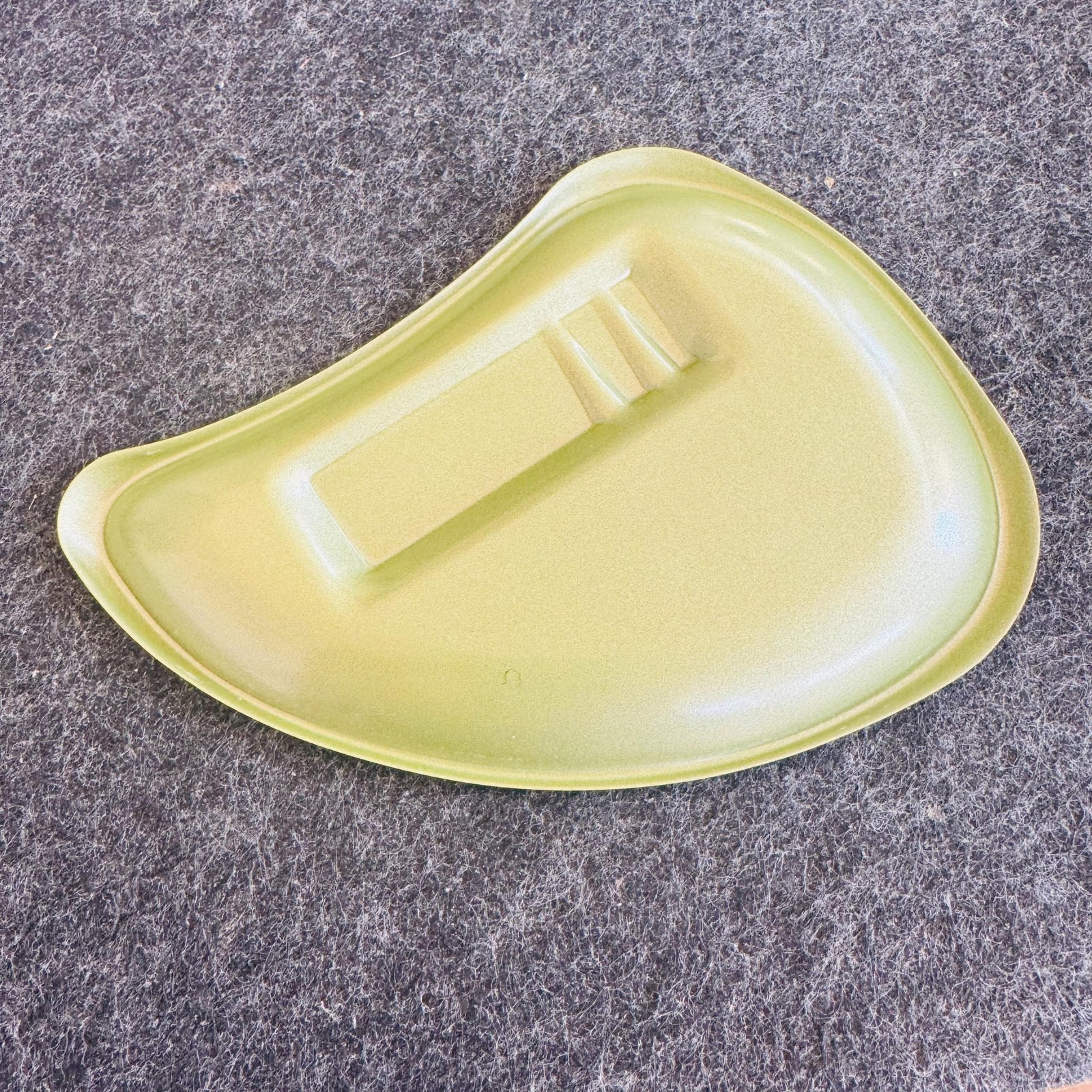 Vintage avocado green boomerang ashtray with black “Get your yield with Fertil-Field” Michigan Bean Co advertising printed in the center.