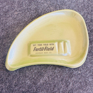 Vintage avocado green boomerang ashtray with black “Get your yield with Fertil-Field” Michigan Bean Co advertising printed in the center.