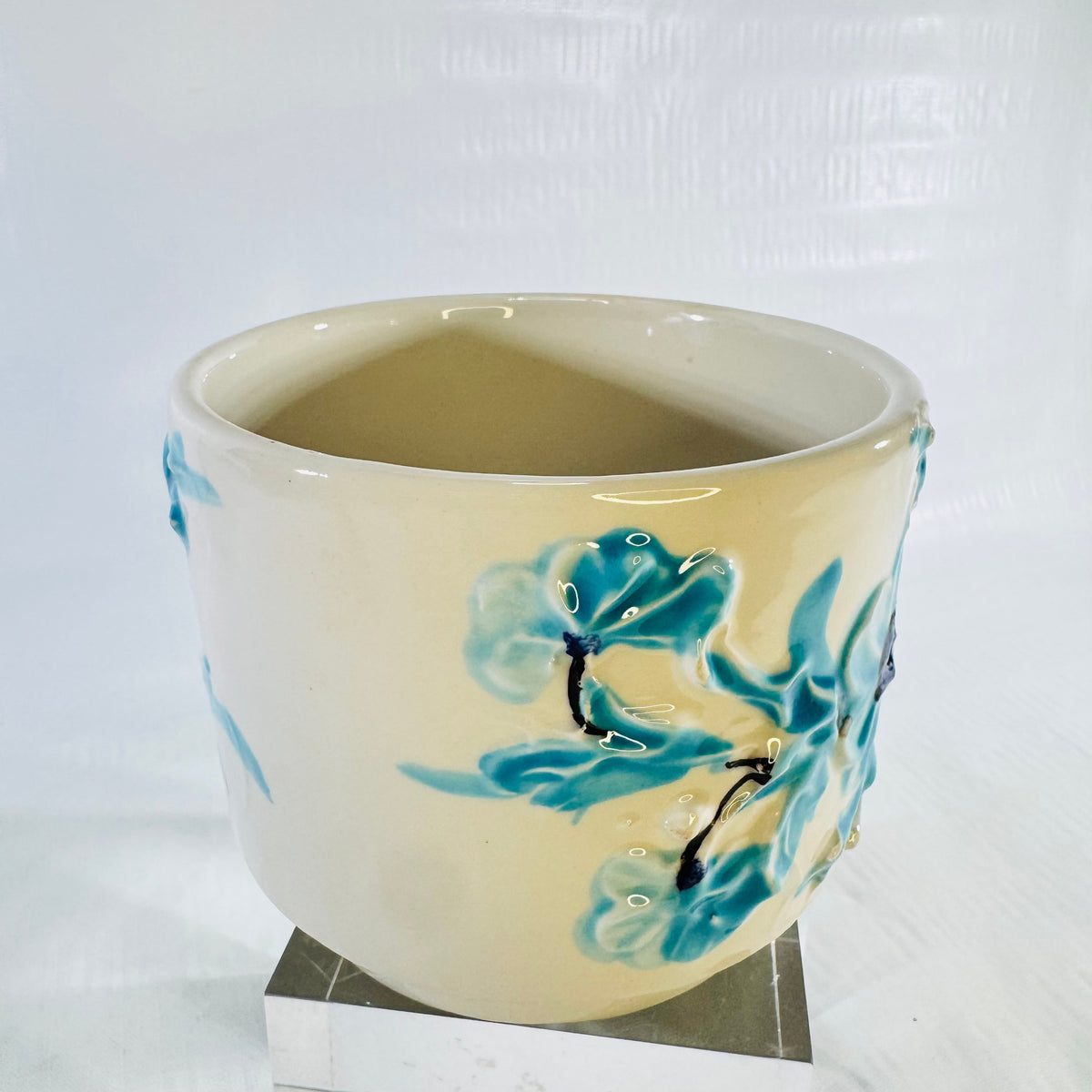 Opposite side of ivory ceramic cachepot with raised blue flowers