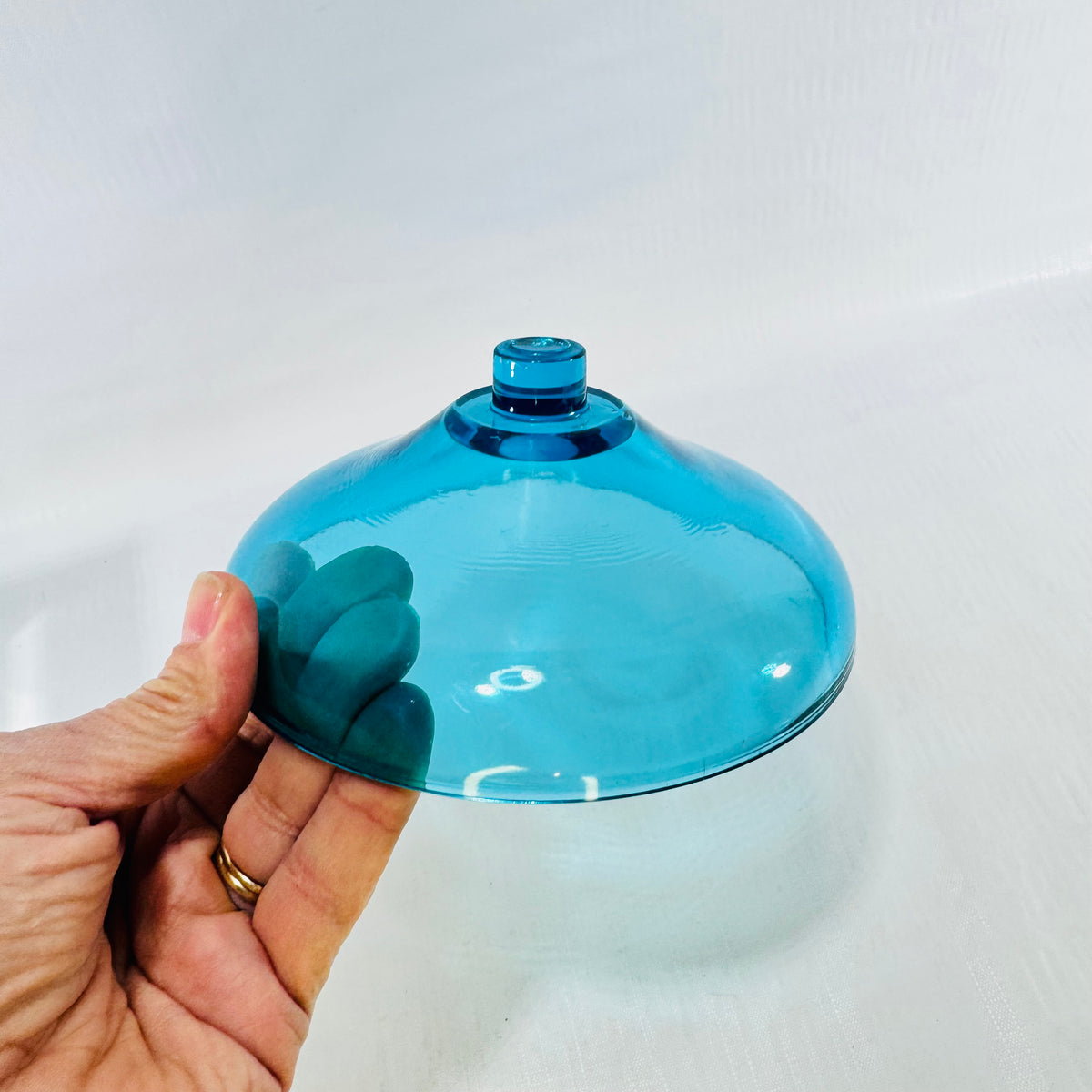 Side view of the turquoise blue bobeche showing the smooth dome and raised center knob