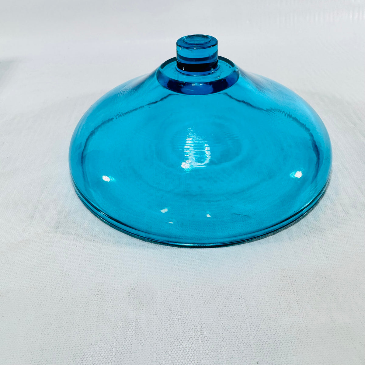 Three quarter view of the turquoise blue glass fairy lamp middle tier on a white surface