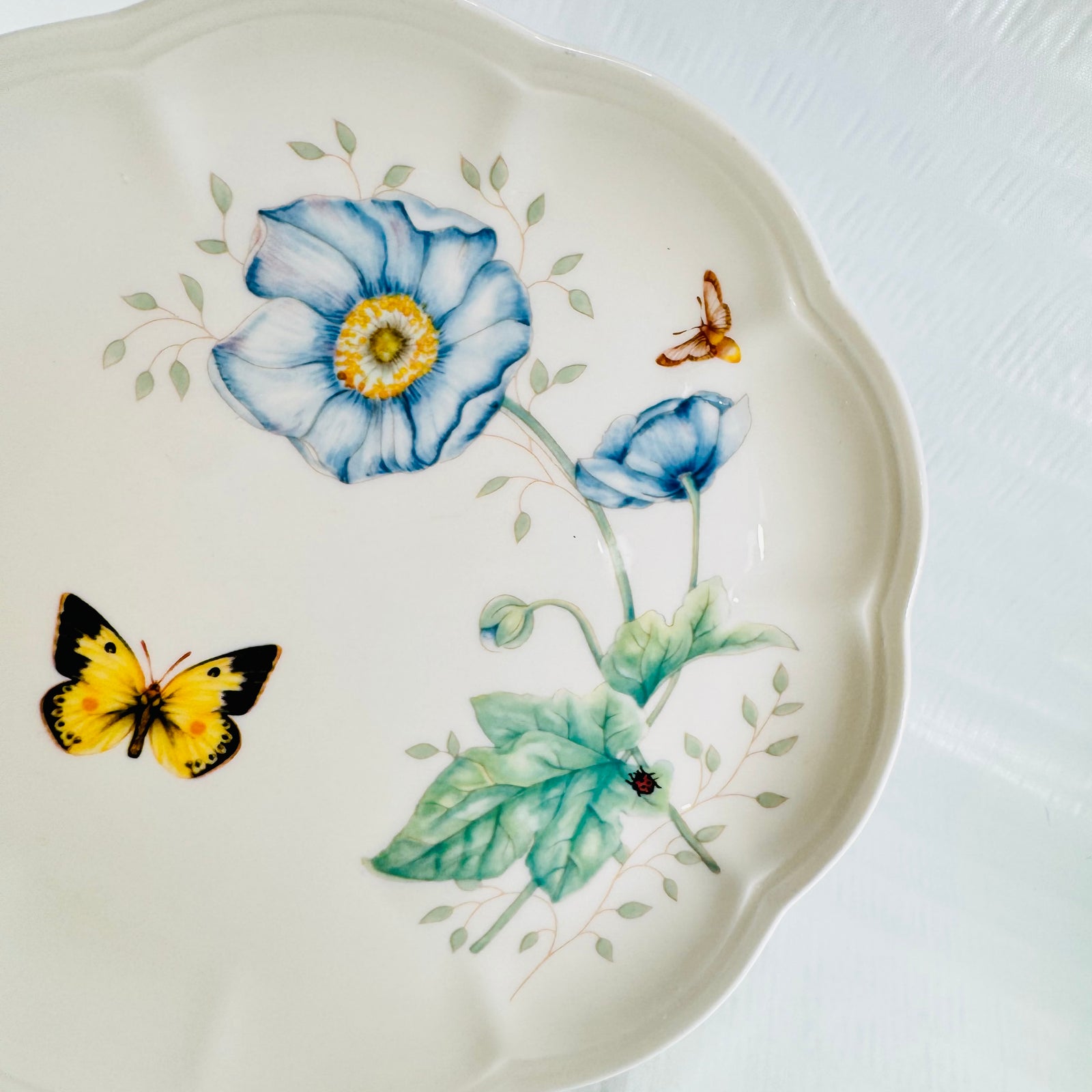 Top down view of Lenox Butterfly Meadow Monarch plate showing blue poppy and yellow butterfly