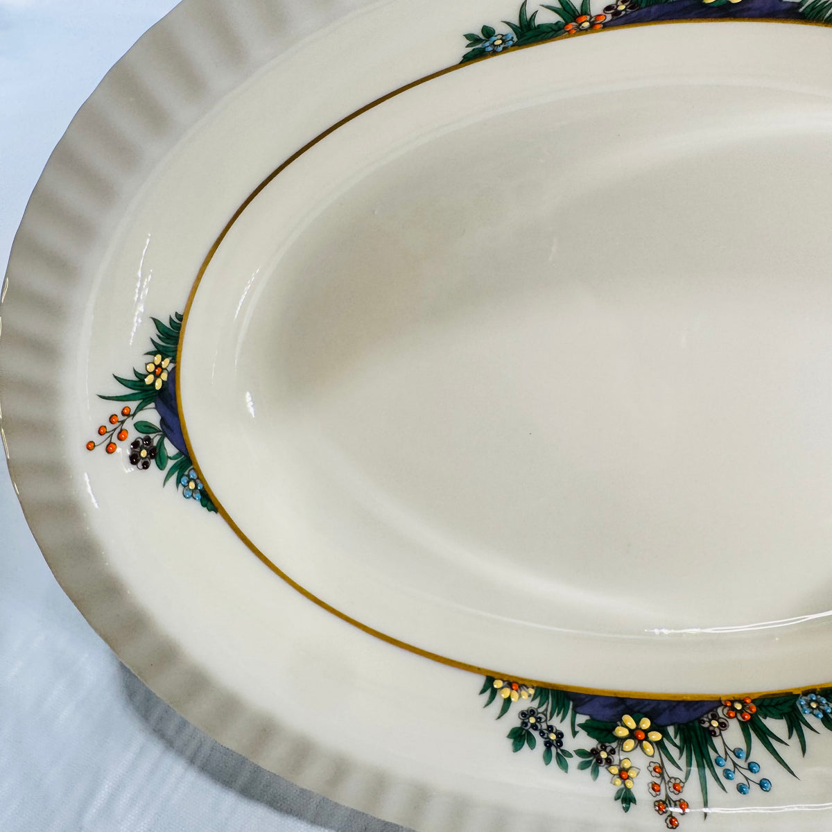Close view of raised enamel flowers and berries along the gold band inside the bowl