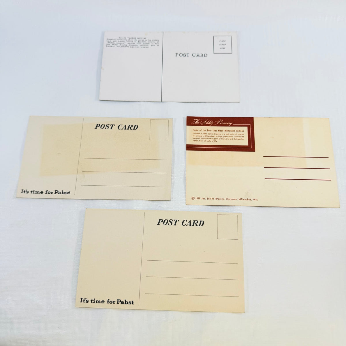 Backs of all four brewery postcards showing printing and age toning