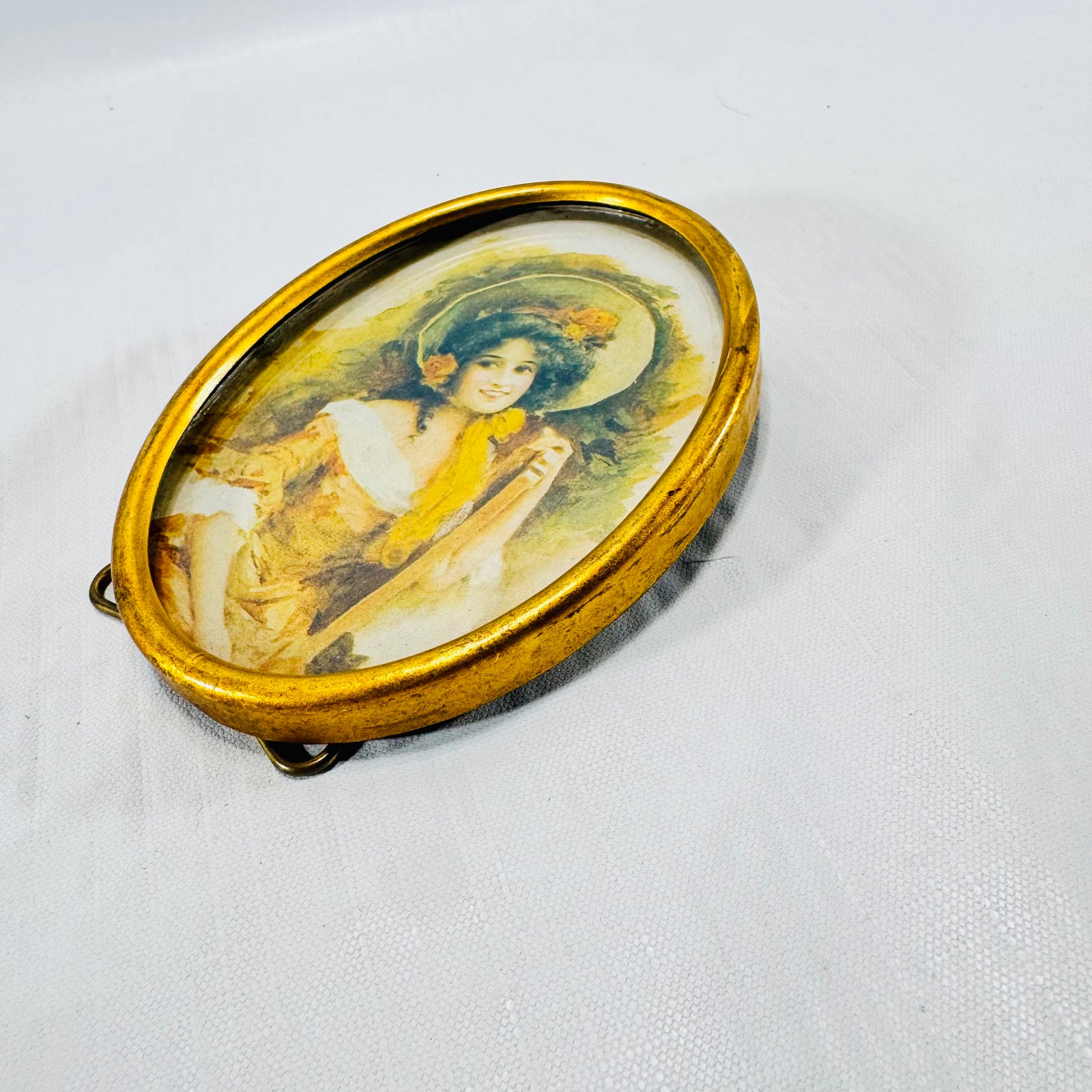 Angled front view of the oval frame showing the bonnet lady print under glass.