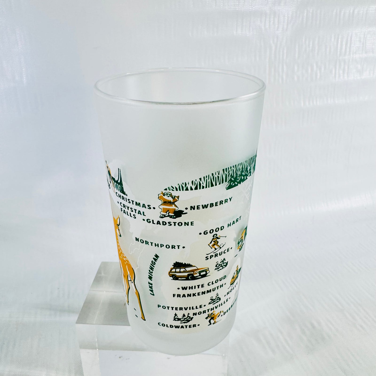Back of the frosted tumbler showing the winter map of Michigan with town names and holiday illustrations.