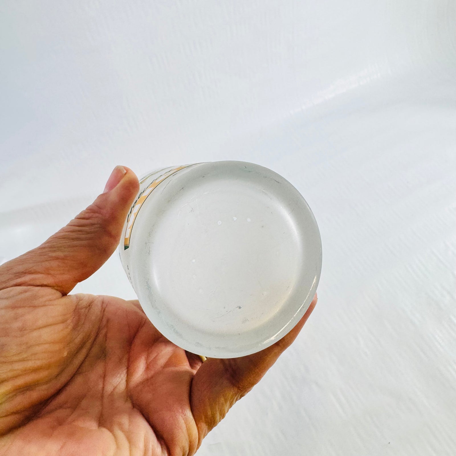 Bottom of the frosted tumbler held up to show the plain base with no maker's mark.
