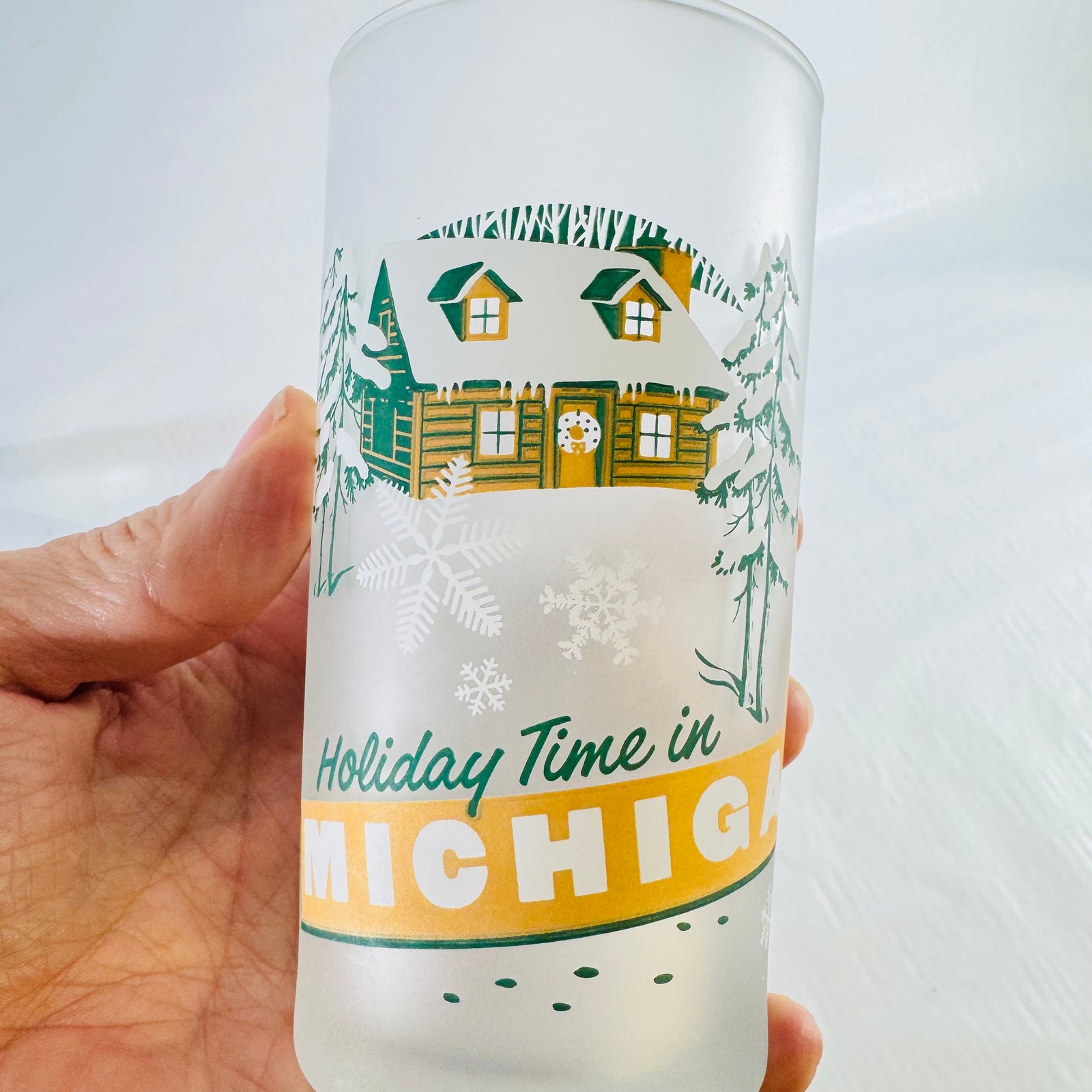 Close up of the cabin graphic on the frosted tumbler held in a hand for scale.