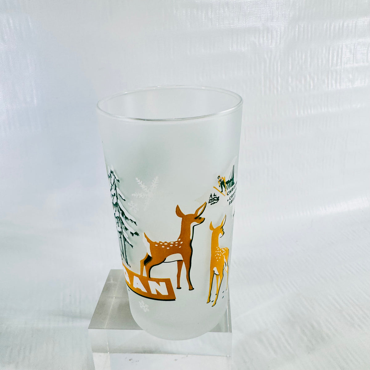 Three quarter view of the frosted tumbler showing two white-tailed deer fawns and snowy pines on the side.
