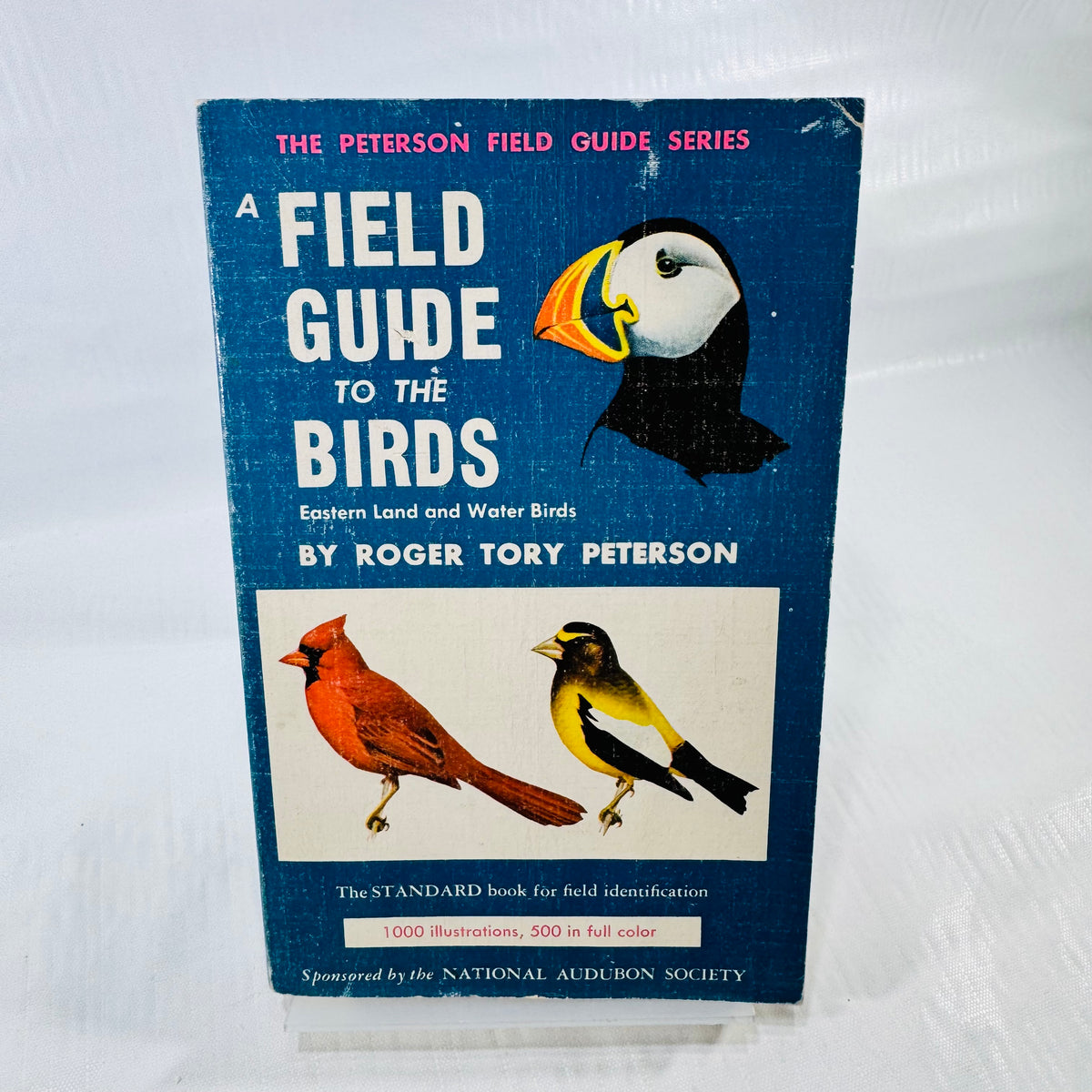 Blue front cover of A Field Guide to the Birds by Roger Tory Peterson, with puffin, cardinal, and goldfinch illustrations and visible rubbing.