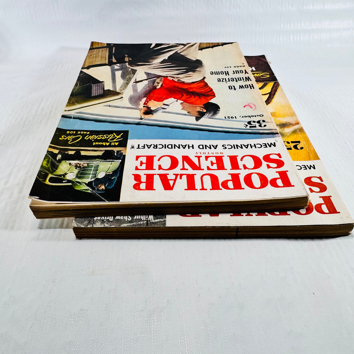 Two issues stacked at an angle with the October 1951 cover on top