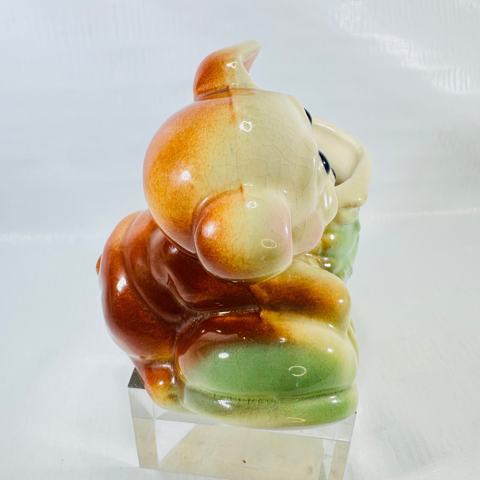 Back of the puppy's head and body with crazed glaze, resting against the green boot.