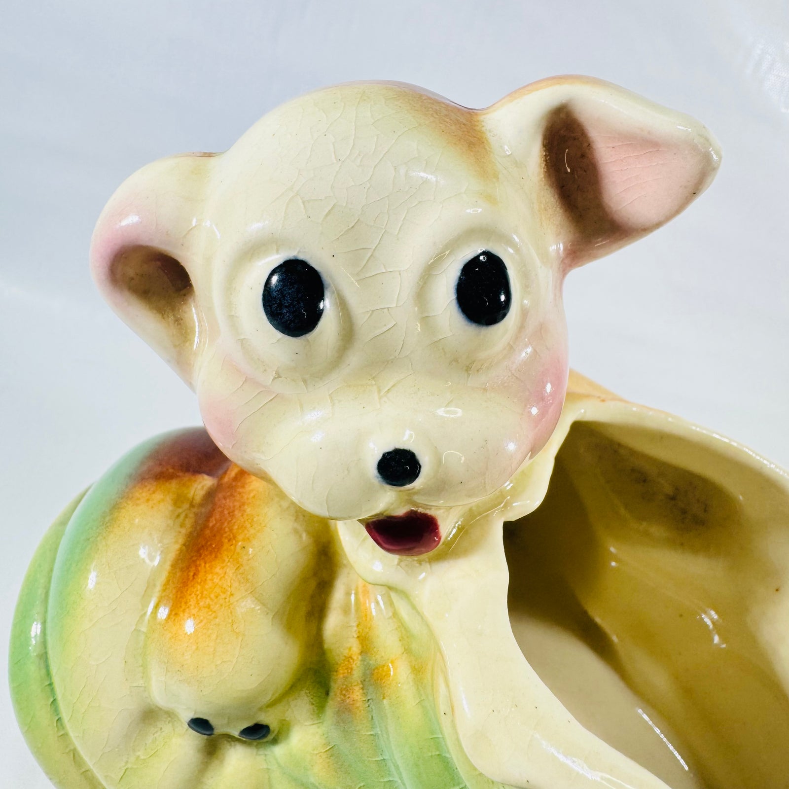 Close up of the puppy's face with black eyes, red mouth, pink cheeks, and crazing in the glaze.