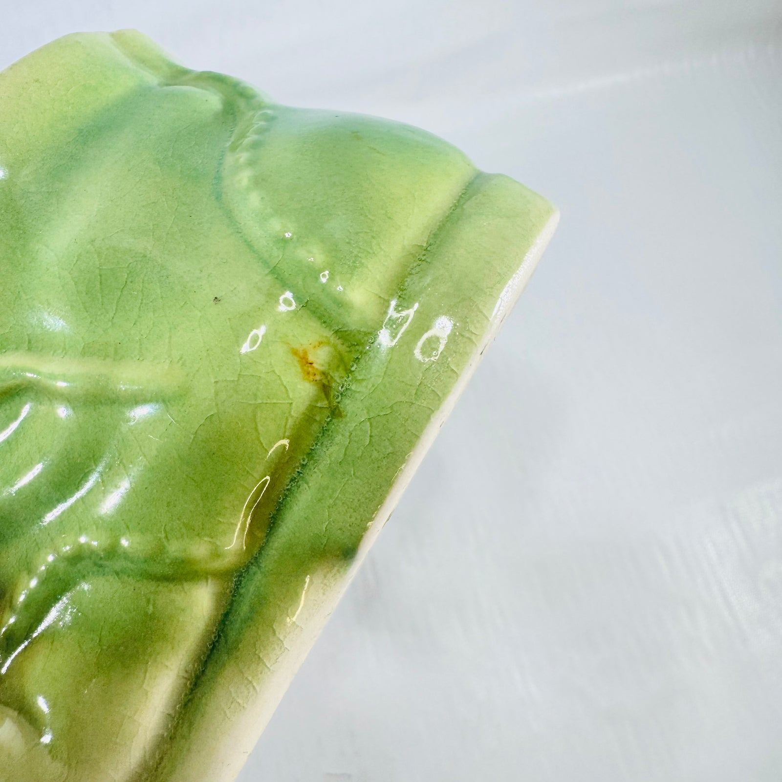 Close up of the green boot glaze showing crazing and a small rust brown speck near a seam.