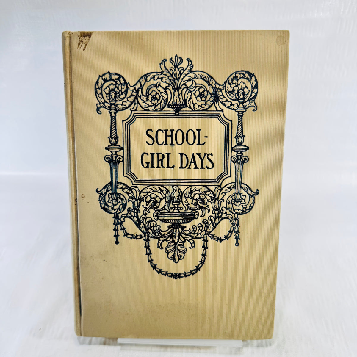 Cream ribbed cloth front cover with dark blue scroll frame and a small chip