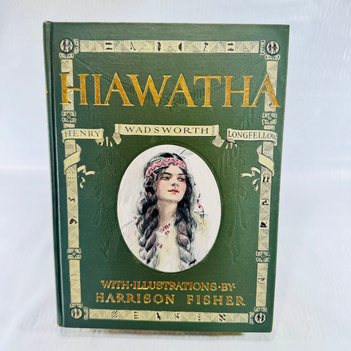 Green cloth front cover with gilt Hiawatha title and inset portrait of a woman