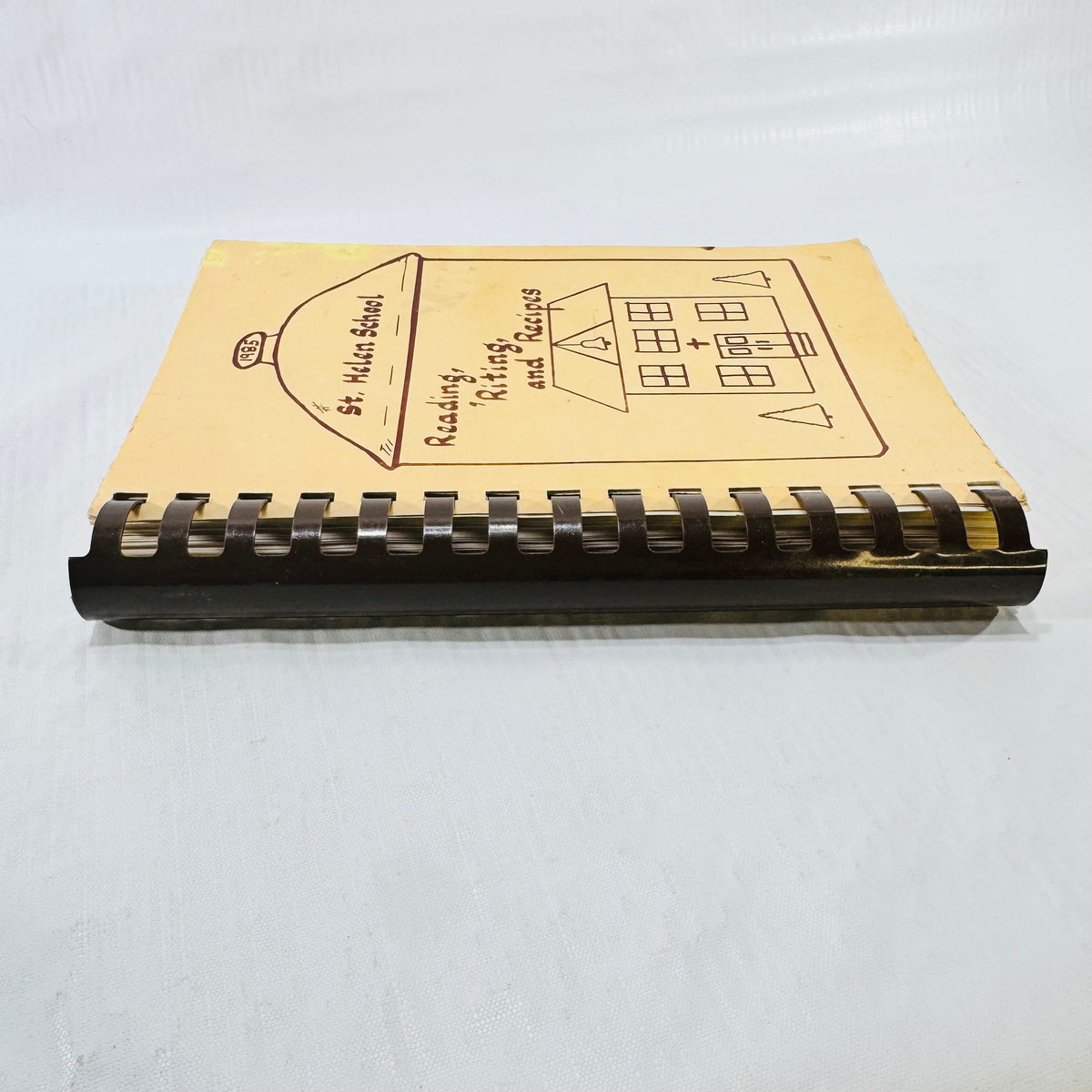 Comb bound spine and page edges of the St. Helen School cookbook