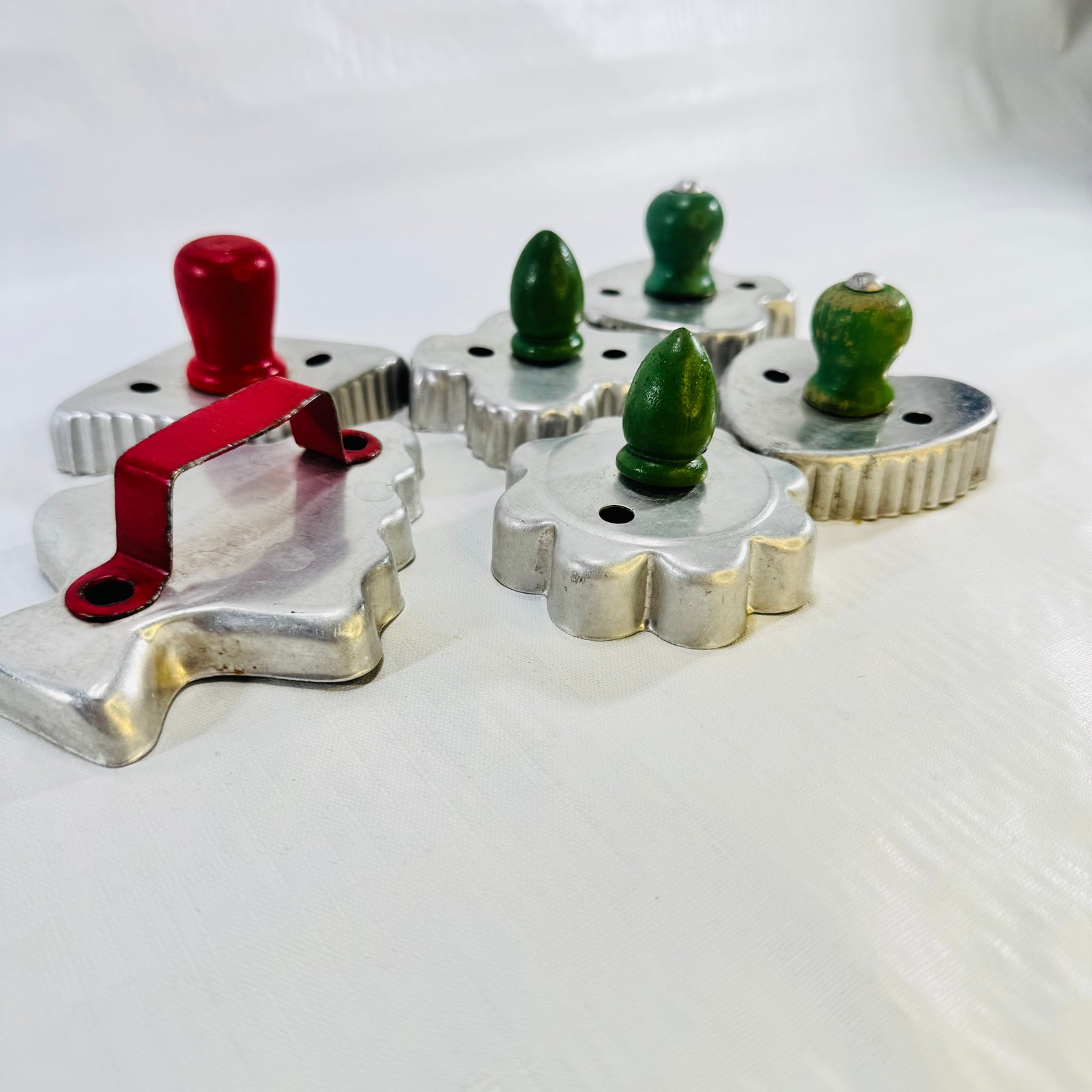 Side view of the aluminum cookie cutters with red strap handle and green wood knobs