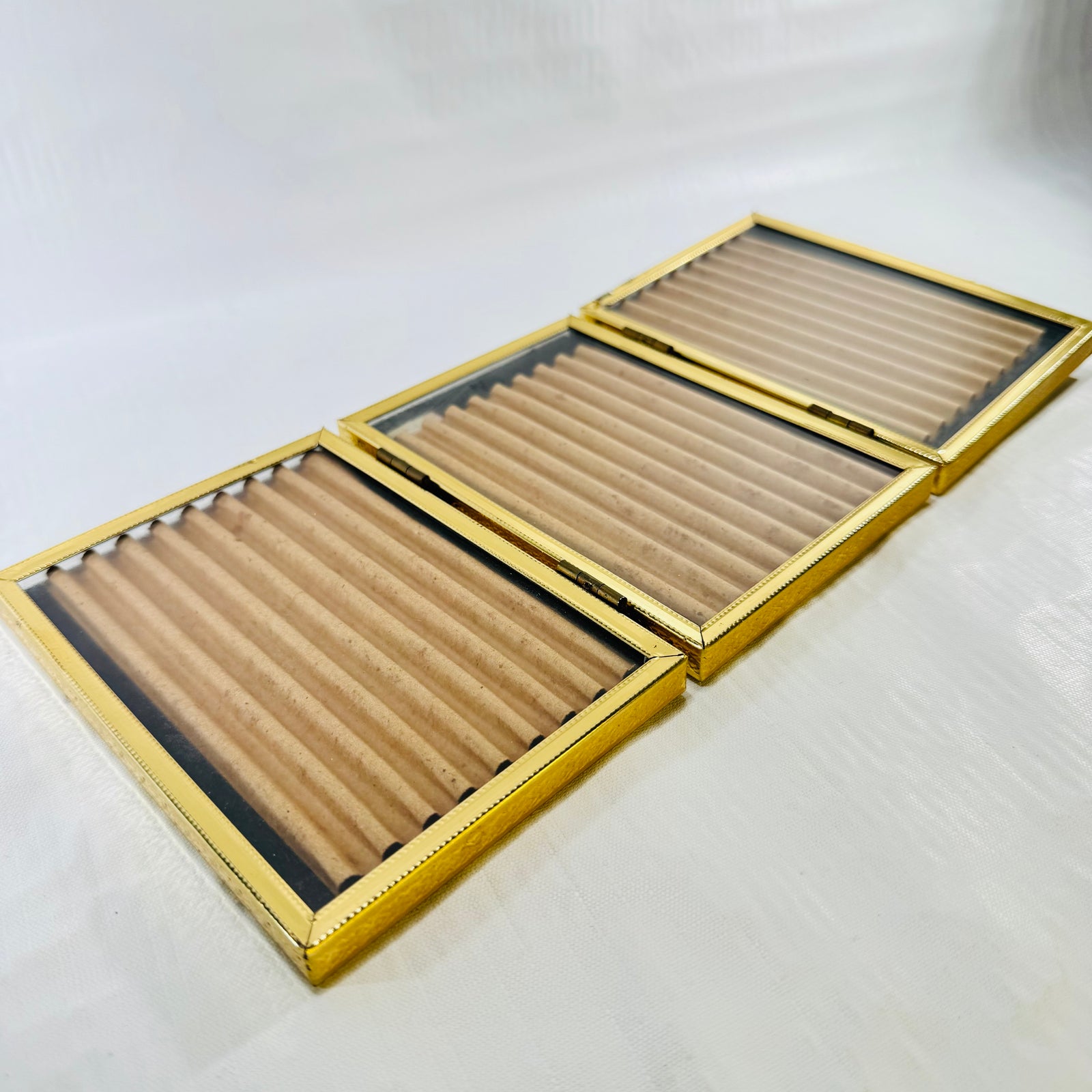 Tri-fold picture frame lying flat at an angle, showing embossed gold tone edges