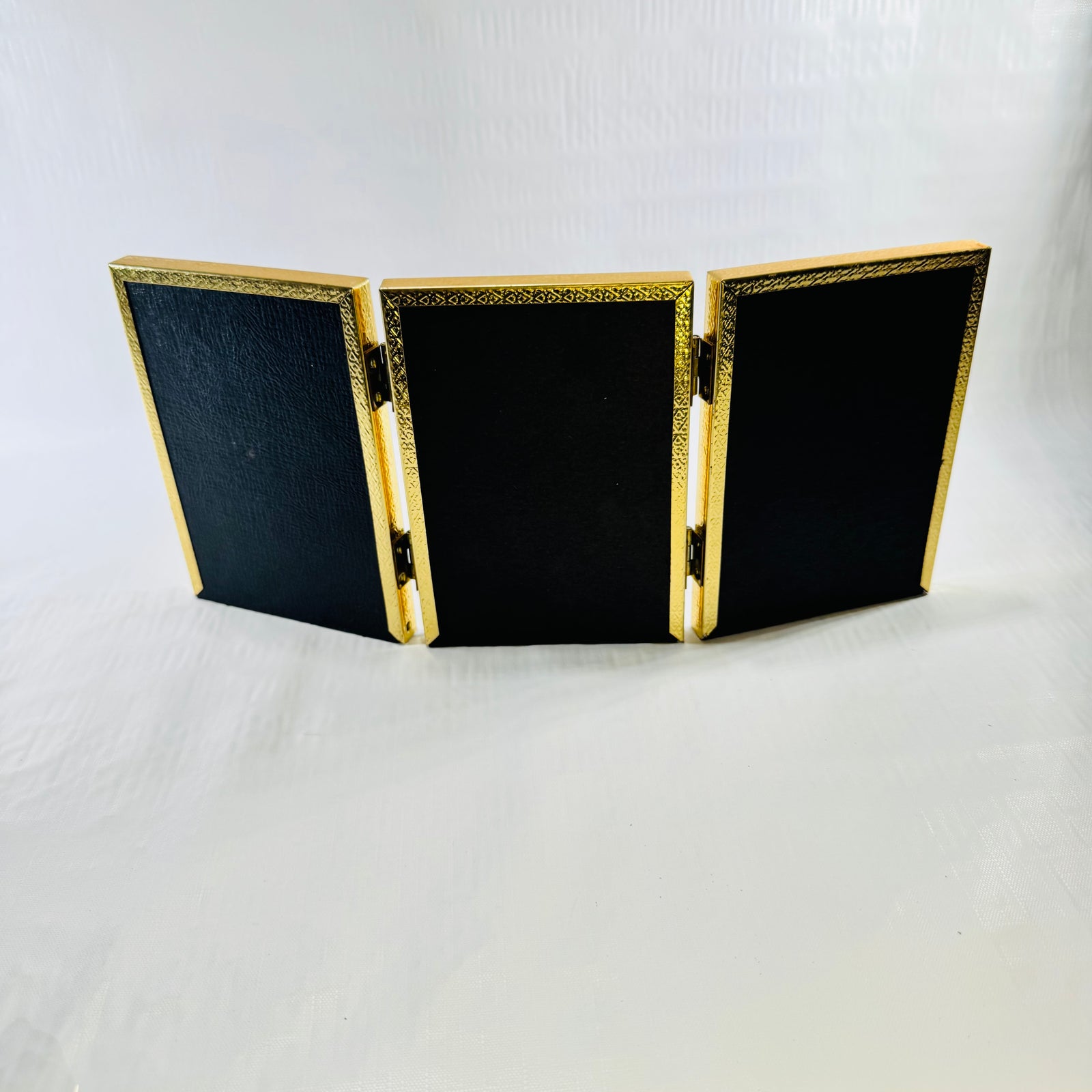 Back of the tri-fold frame with black textured board panels and hinges