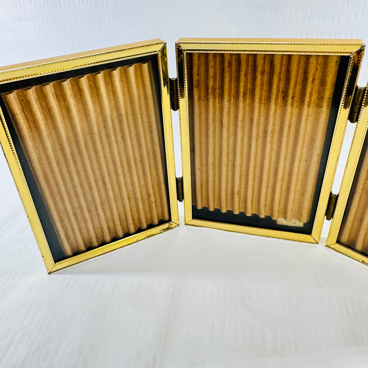 Close-up of the brass tone tri-fold frame showing beaded borders and hinges