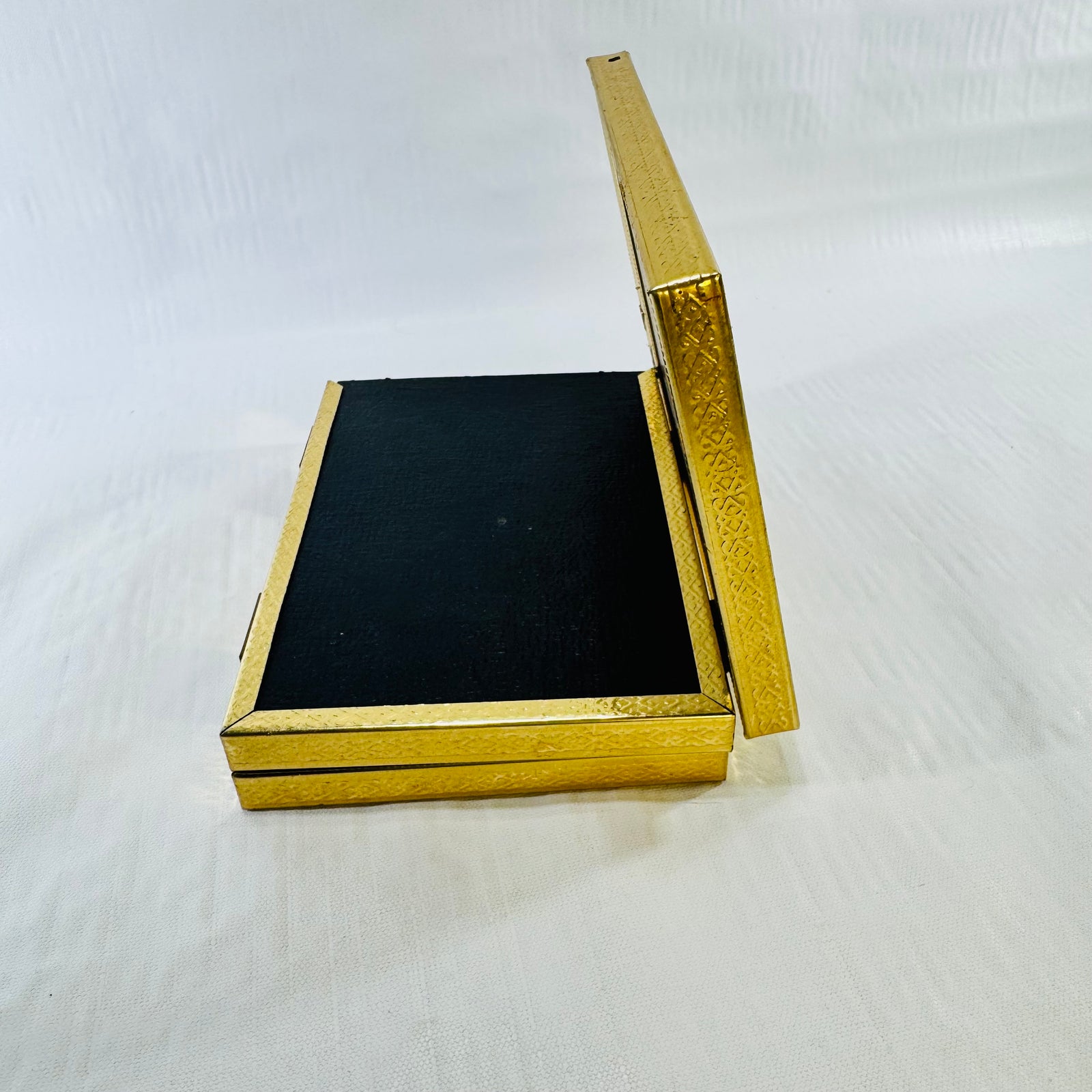 Vintage tri-fold picture frame partly folded, showing black backing and gold edge