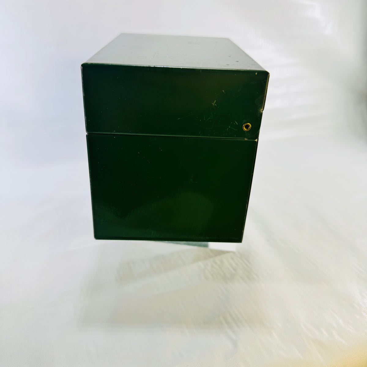 Side of the closed green metal recipe box showing the hinge rivet
