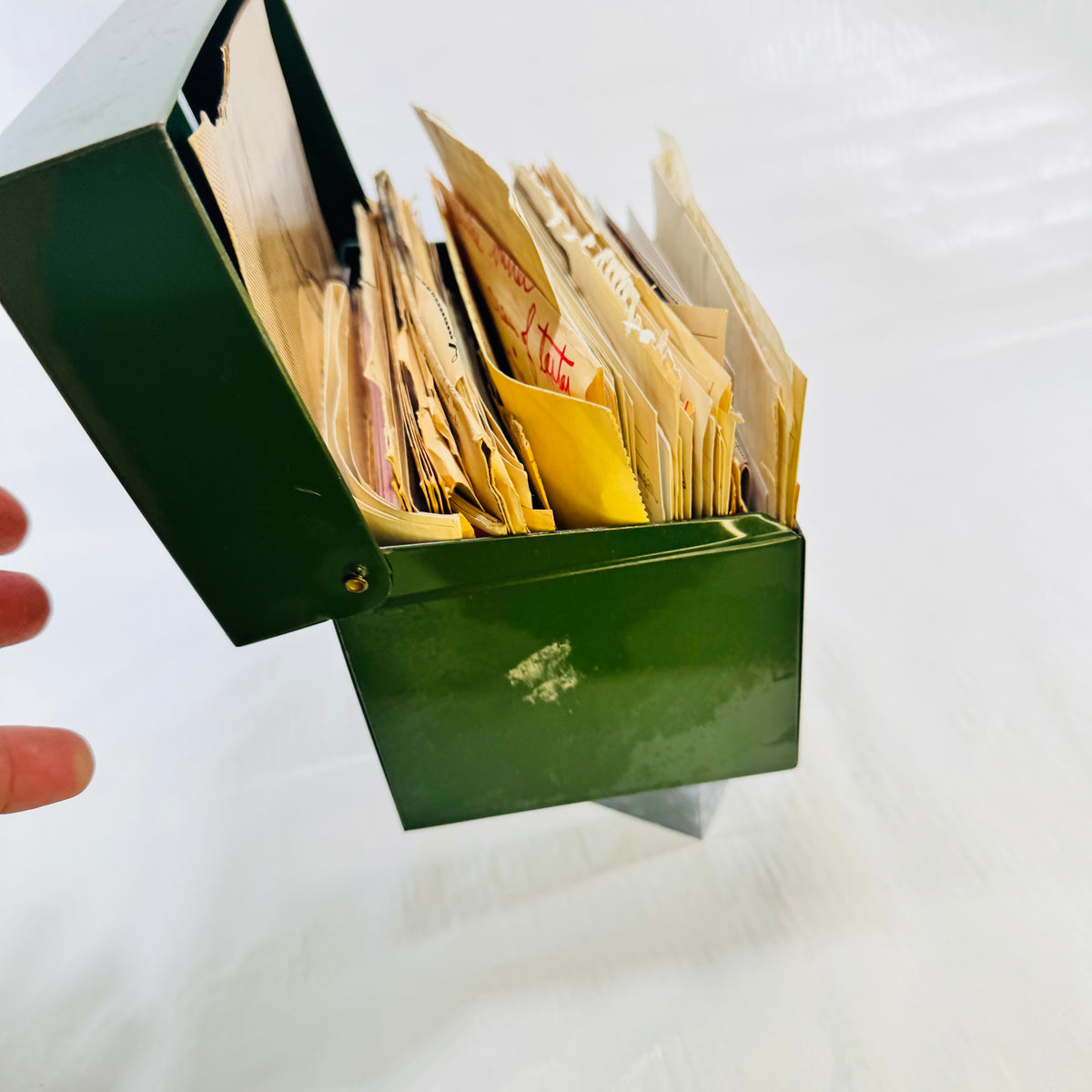 Green metal recipe box with lid open at an angle, showing paint loss on the front
