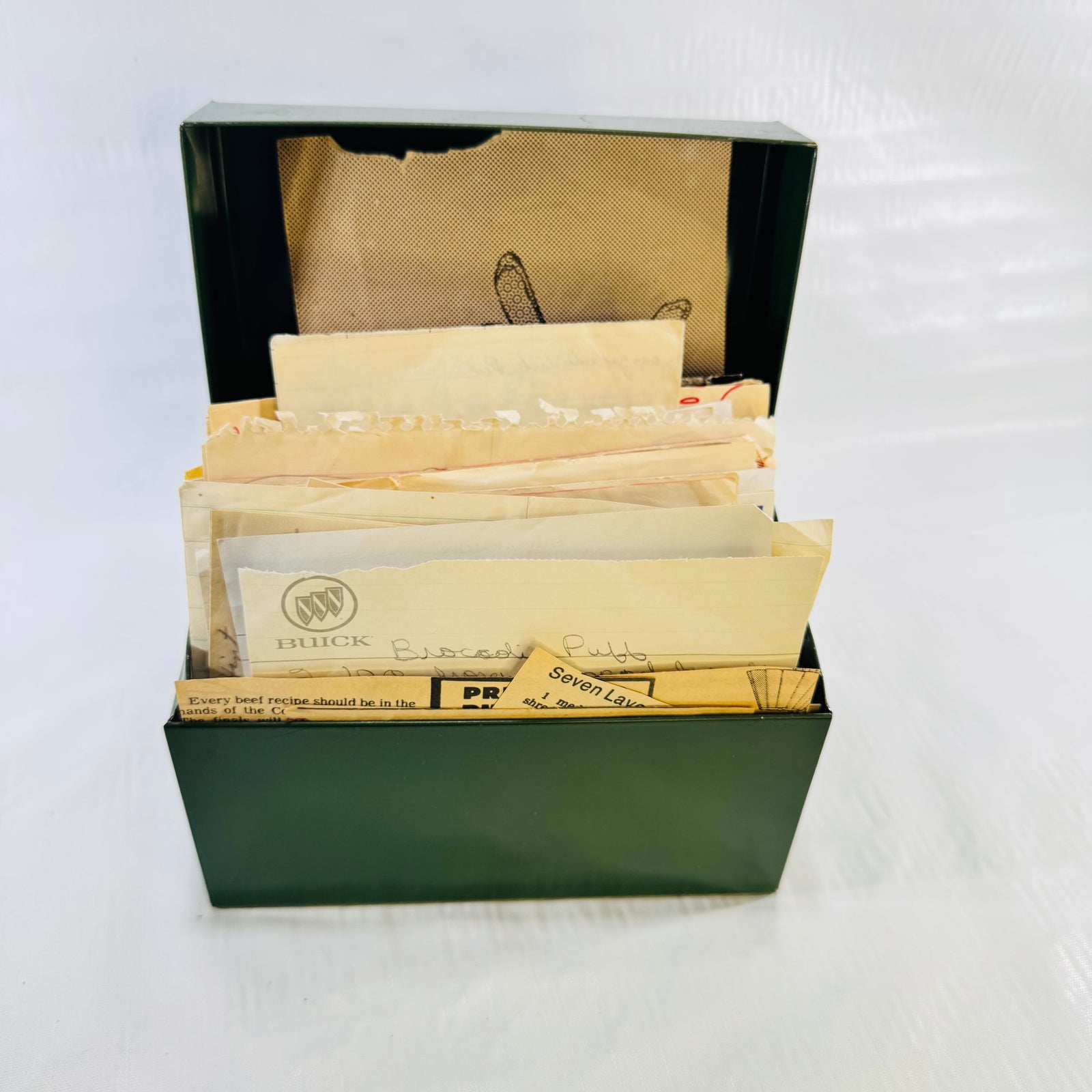 Vintage green metal recipe box open and packed with recipes, Buick broccoli puff card in front