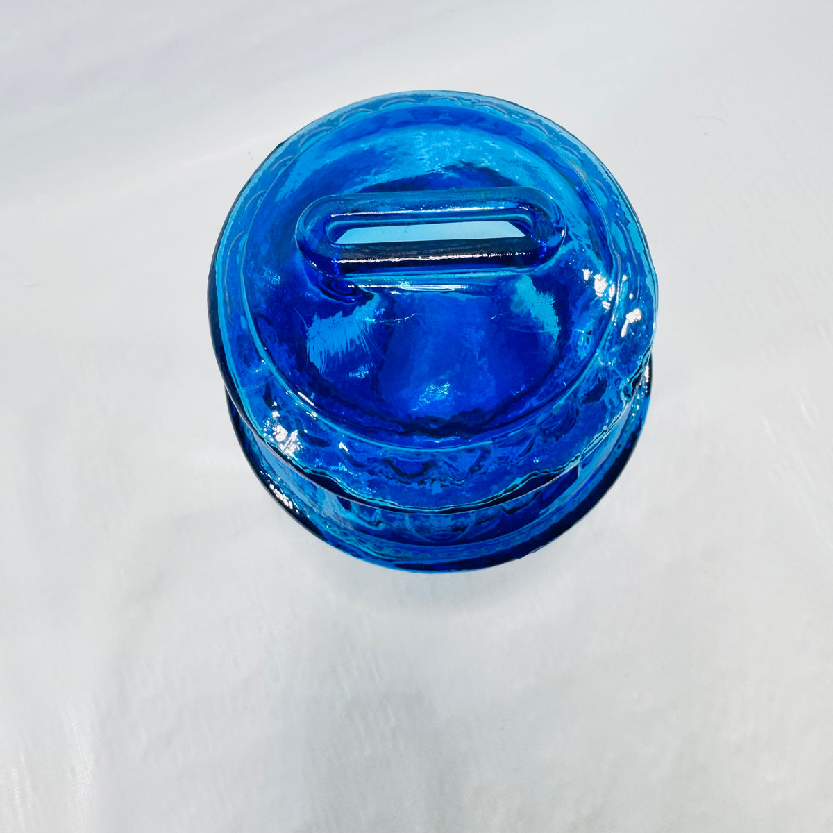 Top view of the Wheaton glass bank showing the raised oval coin slot.