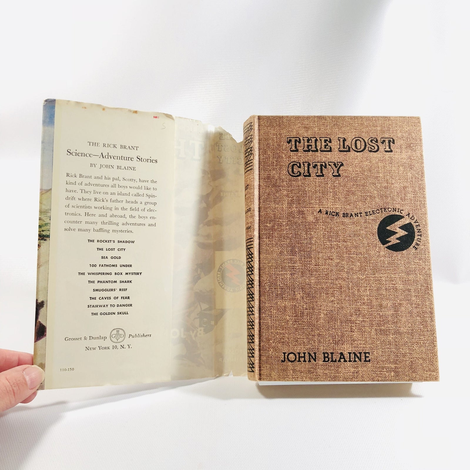 Tan cloth cover with lightning bolt logo, The Lost City by John Blaine